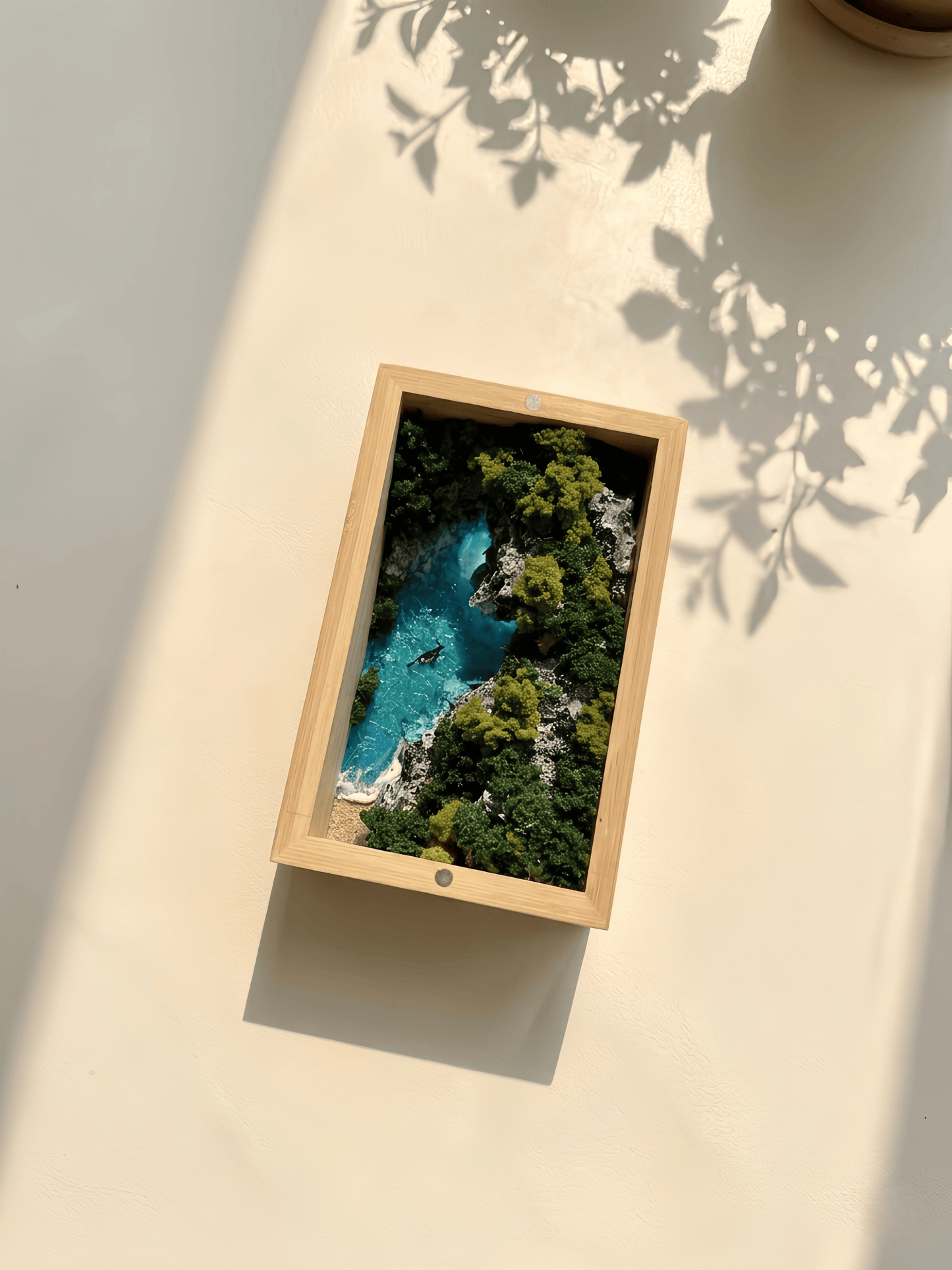 Framed picture of a natural landscape with a lake and trees on a light surface.