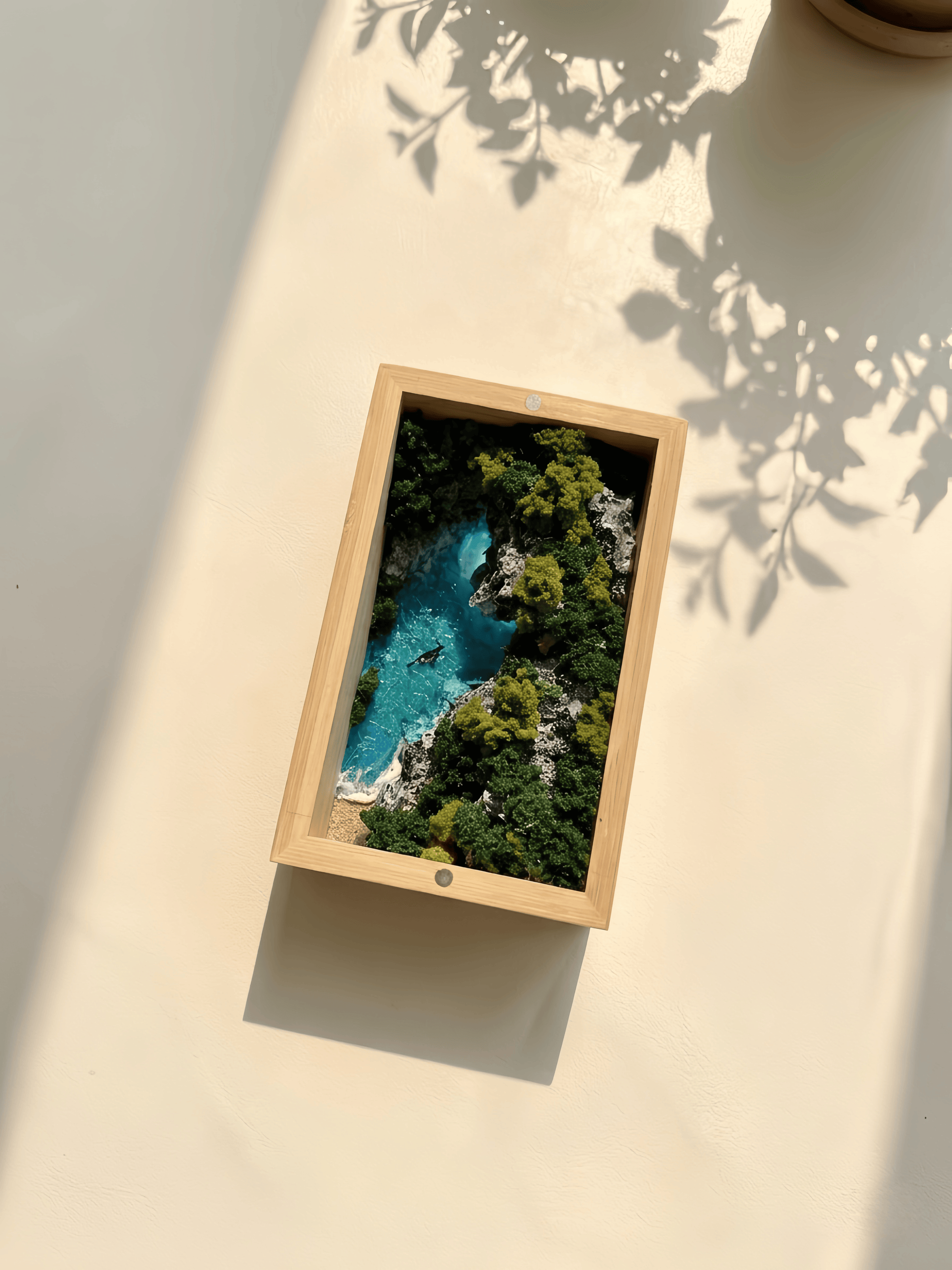 Framed picture of a natural landscape with a lake and trees on a light surface.